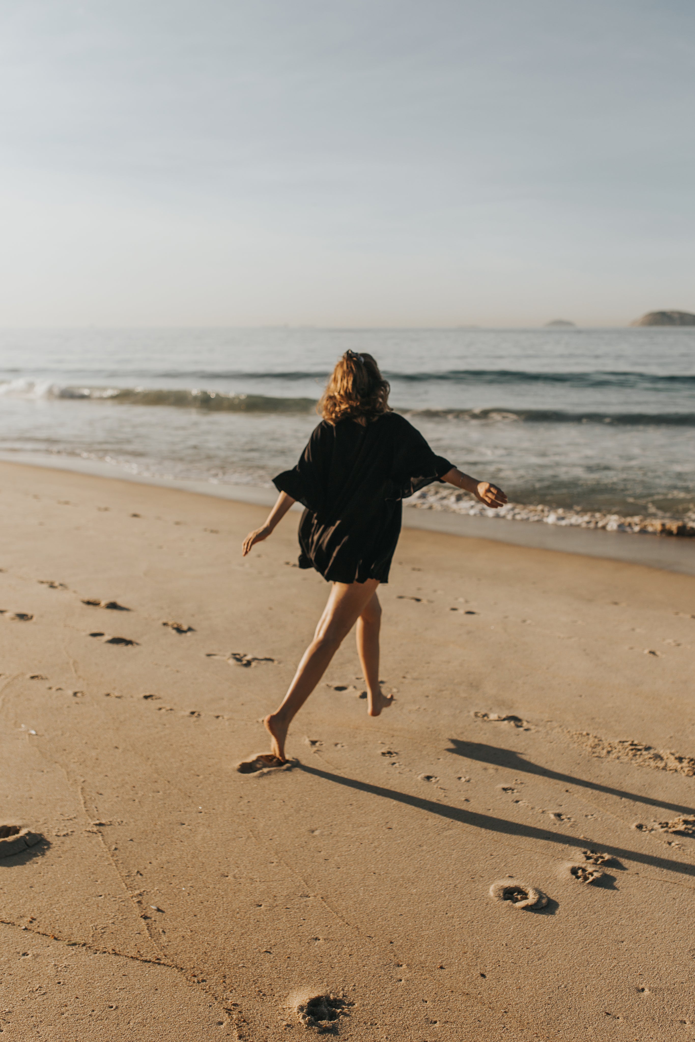 person-in-black-walks-towards-the-water-on-beach.jpg